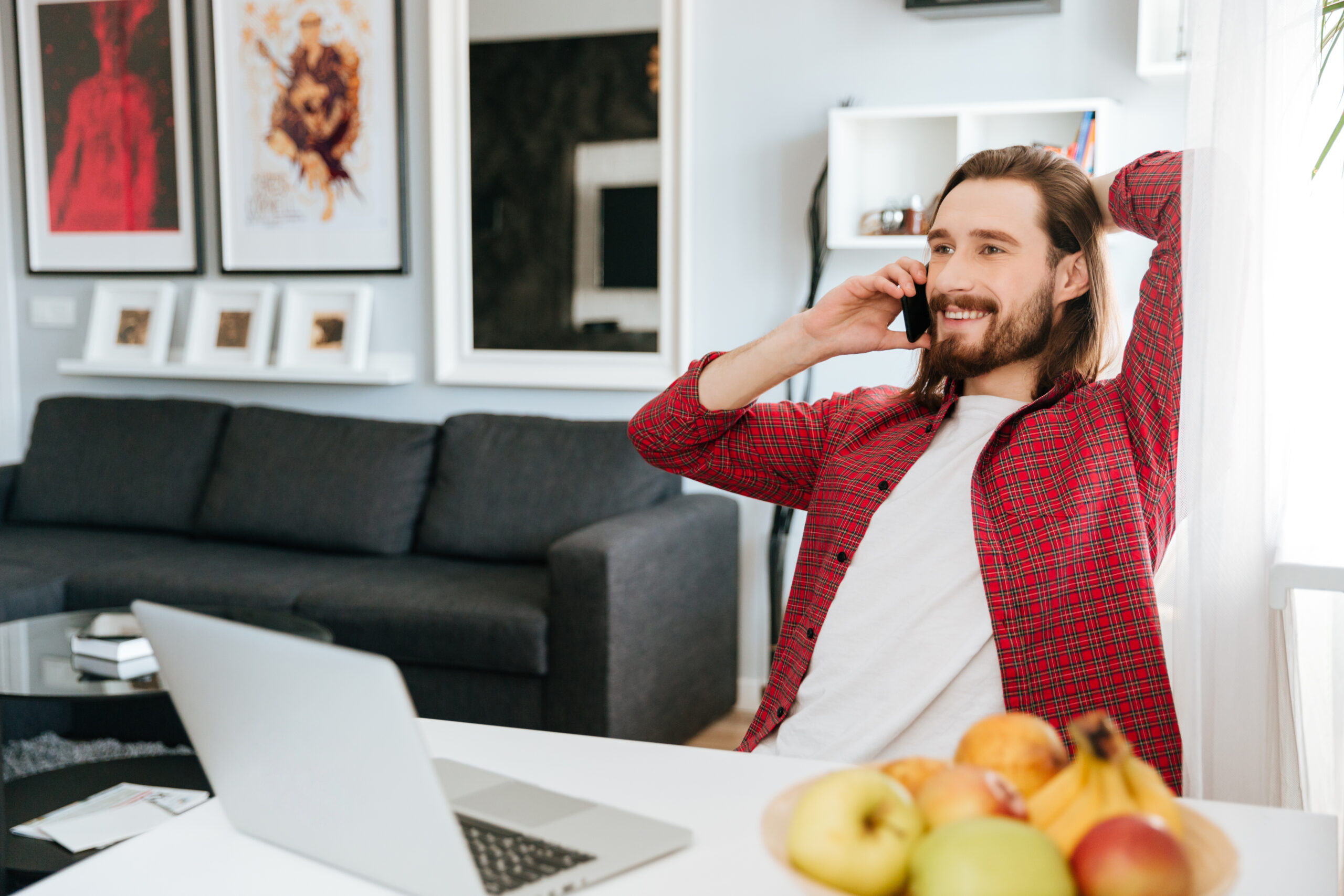 Smiling man working with laptop and talking on mobile phone